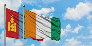 Moğolistan ve Fildişi Sahili bayrağı birlikte beyaz bulutlu mavi gökyüzüne karşı rüzgarda sallayarak. Diplomasi kavramı, uluslararası ilişkiler.