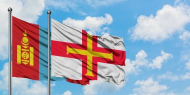 Moğolistan ve Guernsey bayrağı birlikte beyaz bulutlu mavi gökyüzüne karşı rüzgarda sallayarak. Diplomasi kavramı, uluslararası ilişkiler.