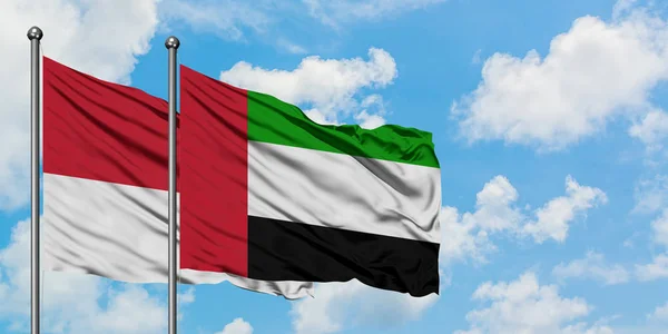 Bandera de Mónaco y Emiratos Árabes Unidos ondeando en el viento contra el cielo azul nublado blanco juntos. Concepto diplomático, relaciones internacionales . — Foto de Stock