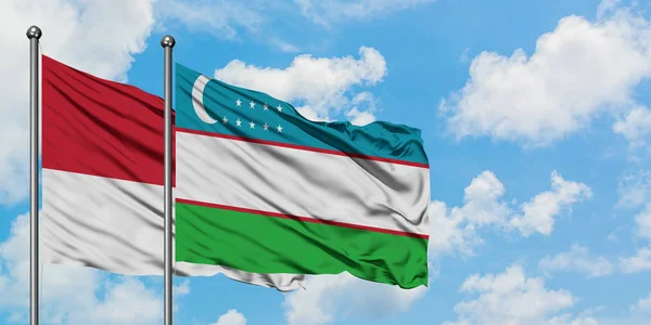 Bandera de Mónaco y Uzbekistán ondeando en el viento contra el cielo azul nublado blanco juntos. Concepto diplomático, relaciones internacionales . — Foto de Stock