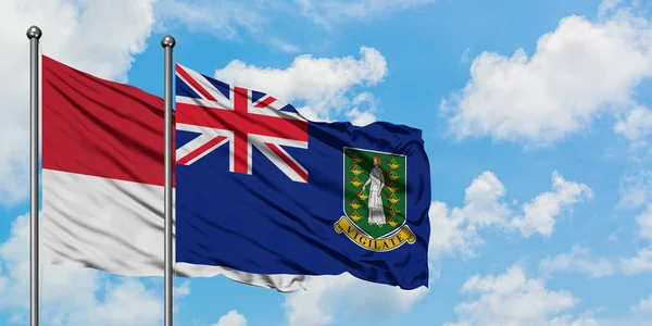 Bandera de Mónaco y las Islas Vírgenes Británicas ondeando en el viento contra el cielo azul nublado blanco juntos. Concepto diplomático, relaciones internacionales . — Foto de Stock