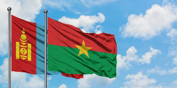 Bandera de Mongolia y Burkina Faso ondeando en el viento contra el cielo azul nublado blanco juntos. Concepto diplomático, relaciones internacionales . — Foto de Stock