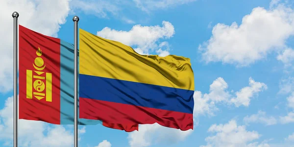 Mongolia e Colombia sventolano nel vento contro il bianco cielo azzurro nuvoloso insieme. Concetto di diplomazia, relazioni internazionali . — Foto Stock