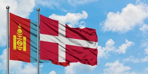 モンゴルとデンマークの国旗が一緒に白い曇り青い空に対して風に振る。外交概念、国際関係. — ストック写真