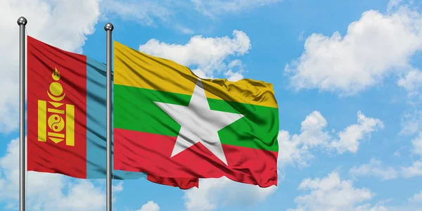 Bandera de Mongolia y Myanmar ondeando en el viento contra el cielo azul nublado blanco juntos. Concepto diplomático, relaciones internacionales . — Foto de Stock