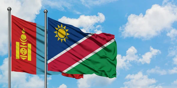 Drapeau de la Mongolie et de la Namibie agitant dans le vent contre ciel bleu nuageux blanc ensemble. Concept de diplomatie, relations internationales . — Photo