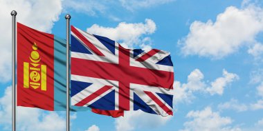 Moğolistan ve Birleşik Krallık bayrağı birlikte beyaz bulutlu mavi gökyüzüne karşı rüzgarda sallayarak. Diplomasi kavramı, uluslararası ilişkiler.