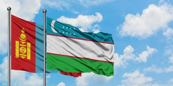 Bandera de Mongolia y Uzbekistán ondeando en el viento contra el cielo azul nublado blanco juntos. Concepto diplomático, relaciones internacionales . — Foto de Stock