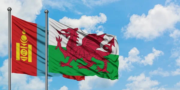 Mongolië en Wales vlag zwaaien in de wind tegen witte bewolkte blauwe hemel samen. Diplomatie concept, internationale betrekkingen. — Stockfoto