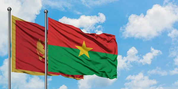 Montenegro y Burkina Faso ondeando en el viento contra el cielo azul nublado blanco juntos. Concepto diplomático, relaciones internacionales . — Foto de Stock