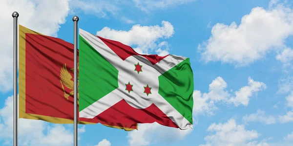 Bandera de Montenegro y Burundi ondeando en el viento contra el cielo azul nublado blanco juntos. Concepto diplomático, relaciones internacionales . — Foto de Stock