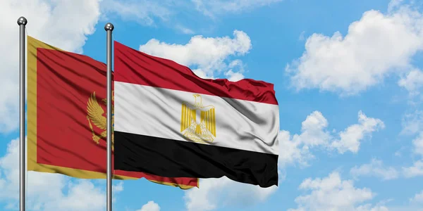 Bandera de Montenegro y Egipto ondeando en el viento contra el cielo azul nublado blanco juntos. Concepto diplomático, relaciones internacionales . — Foto de Stock