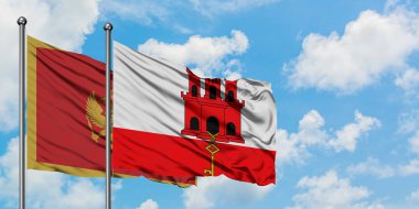 Karadağ ve Cebelitarık bayrağı birlikte beyaz bulutlu mavi gökyüzüne karşı rüzgarda sallayarak. Diplomasi kavramı, uluslararası ilişkiler.