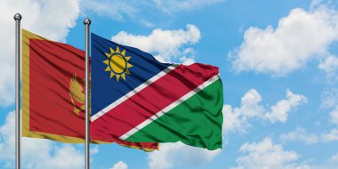 Karadağ ve Namibya bayrağı birlikte beyaz bulutlu mavi gökyüzüne karşı rüzgarda sallayarak. Diplomasi kavramı, uluslararası ilişkiler.