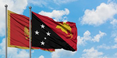 Karadağ ve Papua Yeni Gine bayrağı birlikte beyaz bulutlu mavi gökyüzüne karşı rüzgarsal sallayarak. Diplomasi kavramı, uluslararası ilişkiler.