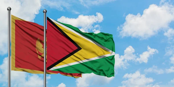 Bandera de Montenegro y Guyana ondeando en el viento contra el cielo azul nublado blanco juntos. Concepto diplomático, relaciones internacionales . — Foto de Stock