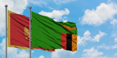 Karadağ ve Zambiya bayrağı birlikte beyaz bulutlu mavi gökyüzüne karşı rüzgarda sallayarak. Diplomasi kavramı, uluslararası ilişkiler.