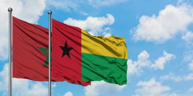 Fas ve Gine Bissau bayrağı birlikte beyaz bulutlu mavi gökyüzüne karşı rüzgarda sallayarak. Diplomasi kavramı, uluslararası ilişkiler.