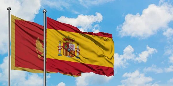 Montenegro und Spanien schwenken gemeinsam die spanische Flagge im Wind gegen den wolkenverhangenen blauen Himmel. Diplomatie-Konzept, internationale Beziehungen. — Stockfoto