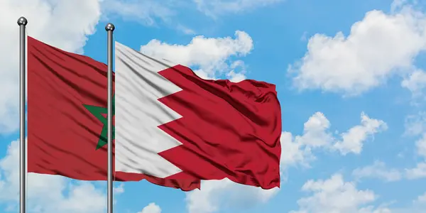 Bandera de Marruecos y Bahréin ondeando en el viento contra el cielo azul nublado blanco juntos. Concepto diplomático, relaciones internacionales . — Foto de Stock