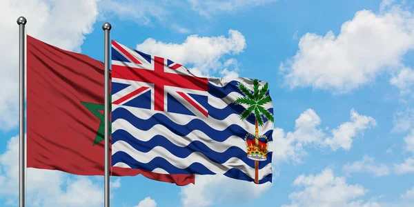 Bandera de Marruecos y del Territorio Británico del Océano Índico ondeando en el viento contra el cielo azul nublado blanco juntos. Concepto diplomático, relaciones internacionales . — Foto de Stock