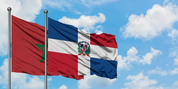 Bandera de Marruecos y República Dominicana ondeando en el viento contra el cielo azul nublado blanco juntos. Concepto diplomático, relaciones internacionales . — Foto de Stock