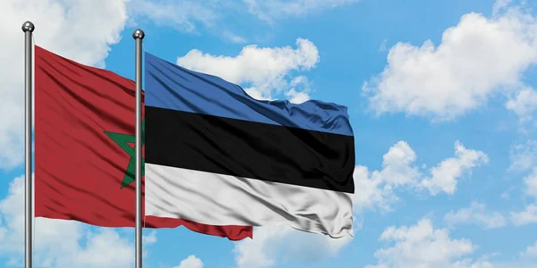 Bandera de Marruecos y Estonia ondeando en el viento contra el cielo azul nublado blanco juntos. Concepto diplomático, relaciones internacionales . — Foto de Stock
