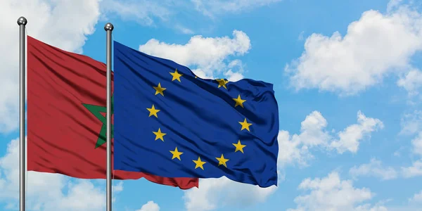 Bandera de Marruecos y la Unión Europea ondeando en el viento contra el cielo azul nublado blanco juntos. Concepto diplomático, relaciones internacionales . — Foto de Stock