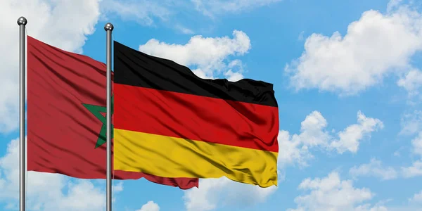 Bandera de Marruecos y Alemania ondeando en el viento contra el cielo azul nublado blanco juntos. Concepto diplomático, relaciones internacionales . — Foto de Stock