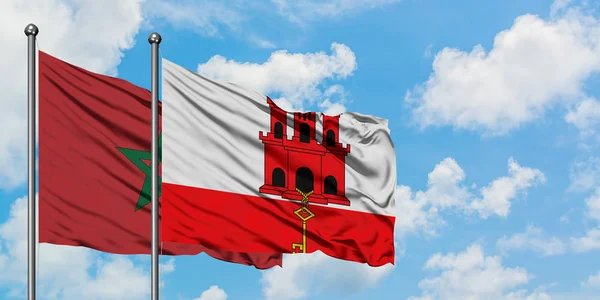 Bandera de Marruecos y Gibraltar ondeando en el viento contra el cielo azul nublado blanco juntos. Concepto diplomático, relaciones internacionales . — Foto de Stock