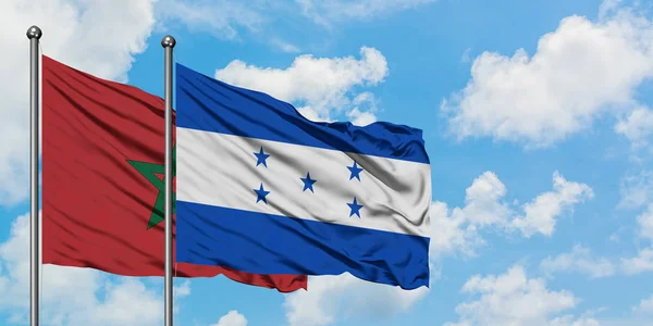 Bandera de Marruecos y Honduras ondeando en el viento contra el cielo azul nublado blanco juntos. Concepto diplomático, relaciones internacionales . — Foto de Stock