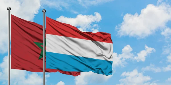 Bandera de Marruecos y Luxemburgo ondeando en el viento contra el cielo azul nublado blanco juntos. Concepto diplomático, relaciones internacionales . — Foto de Stock