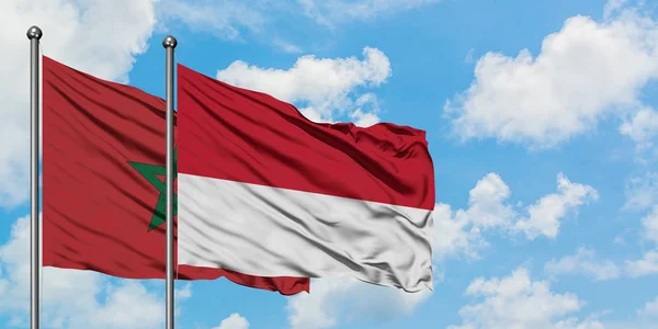 Bandera de Marruecos y Mónaco ondeando en el viento contra el cielo azul nublado blanco juntos. Concepto diplomático, relaciones internacionales . — Foto de Stock