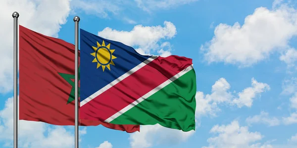Bandera de Marruecos y Namibia ondeando en el viento contra el cielo azul nublado blanco juntos. Concepto diplomático, relaciones internacionales . — Foto de Stock