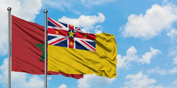 Bandera de Marruecos y Niue ondeando en el viento contra el cielo azul nublado blanco juntos. Concepto diplomático, relaciones internacionales . — Foto de Stock