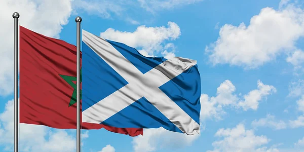 Bandera de Marruecos y Escocia ondeando en el viento contra el cielo azul nublado blanco juntos. Concepto diplomático, relaciones internacionales . — Foto de Stock