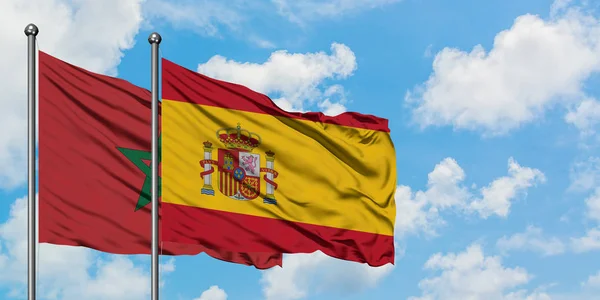 Marokko und Spanien schwenken gemeinsam die spanische Flagge im Wind gegen den wolkenverhangenen blauen Himmel. Diplomatie-Konzept, internationale Beziehungen. — Stockfoto