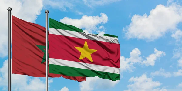 Bandera de Marruecos y Surinam ondeando en el viento contra el cielo azul nublado blanco juntos. Concepto diplomático, relaciones internacionales . — Foto de Stock