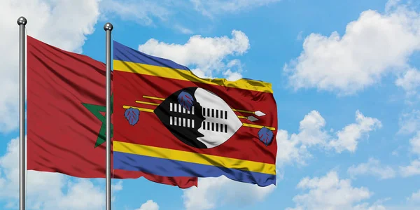 Bandera de Marruecos y Suazilandia ondeando en el viento contra el cielo azul nublado blanco juntos. Concepto diplomático, relaciones internacionales . — Foto de Stock