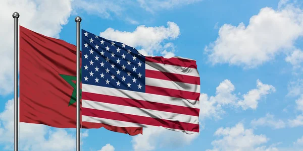 Bandera de Marruecos y Estados Unidos ondeando en el viento contra el cielo azul nublado blanco juntos. Concepto diplomático, relaciones internacionales . — Foto de Stock