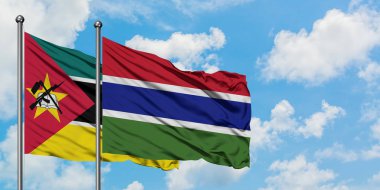 Mozambik ve Gambiya bayrağı birlikte beyaz bulutlu mavi gökyüzüne karşı rüzgarda sallayarak. Diplomasi kavramı, uluslararası ilişkiler.