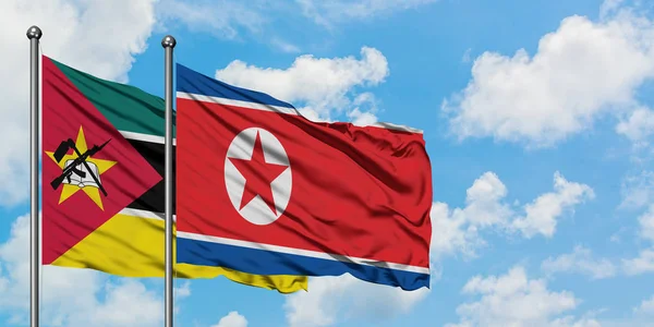Moçambique e a Coreia do Norte acenando com o vento contra o céu azul nublado branco juntos. Conceito de diplomacia, relações internacionais . — Fotografia de Stock