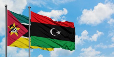 Mozambik ve Libya bayrağı birlikte beyaz bulutlu mavi gökyüzüne karşı rüzgarsal sallayarak. Diplomasi kavramı, uluslararası ilişkiler.