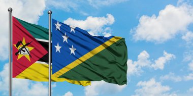 Mozambik ve Solomon Adaları bayrağı birlikte beyaz bulutlu mavi gökyüzüne karşı rüzgarda sallayarak. Diplomasi kavramı, uluslararası ilişkiler.