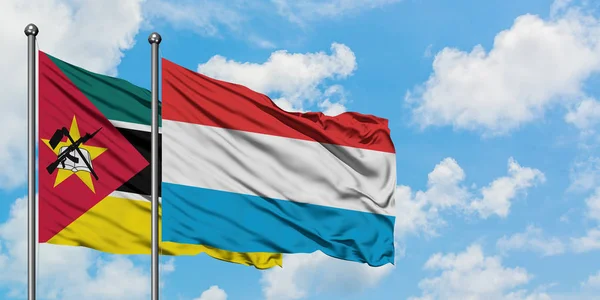 Bandera de Mozambique y Luxemburgo ondeando en el viento contra el cielo azul nublado blanco juntos. Concepto diplomático, relaciones internacionales . — Foto de Stock