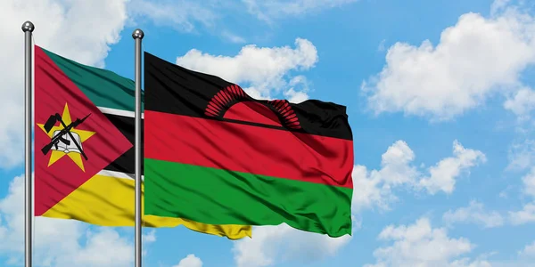 Moçambique e a bandeira do Malawi agitando no vento contra o céu azul nublado branco juntos. Conceito de diplomacia, relações internacionais . — Fotografia de Stock