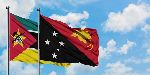 Mozambique and Papua New Guinea flag waving in the wind against white cloudy blue sky together. Diplomacy concept, international relations. — Stock Photo, Image