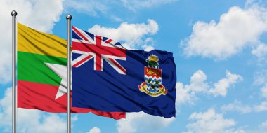 Myanmar ve Cayman Adaları bayrağı birlikte beyaz bulutlu mavi gökyüzüne karşı rüzgarsal sallayarak. Diplomasi kavramı, uluslararası ilişkiler.