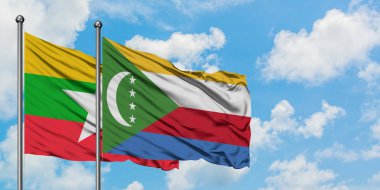 Myanmar ve Komorbayrağı birlikte beyaz bulutlu mavi gökyüzüne karşı rüzgarda sallayarak. Diplomasi kavramı, uluslararası ilişkiler.