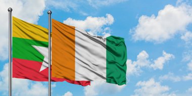 Myanmar ve Fildişi Sahili bayrağı birlikte beyaz bulutlu mavi gökyüzüne karşı rüzgarda sallayarak. Diplomasi kavramı, uluslararası ilişkiler.